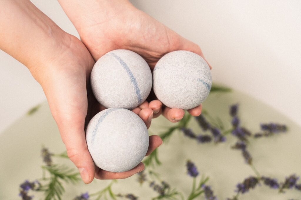 Three Eir Health CBD bath bombs slowly dissolve in a warm bath, their effervescence creating a soothing and relaxing ambiance. Each bath bomb introduces a different hue to the water, painting a serene, color-infused picture of chill time. This image perfectly encapsulates the multi-sensory relaxation experience offered by these innovative wellness products.